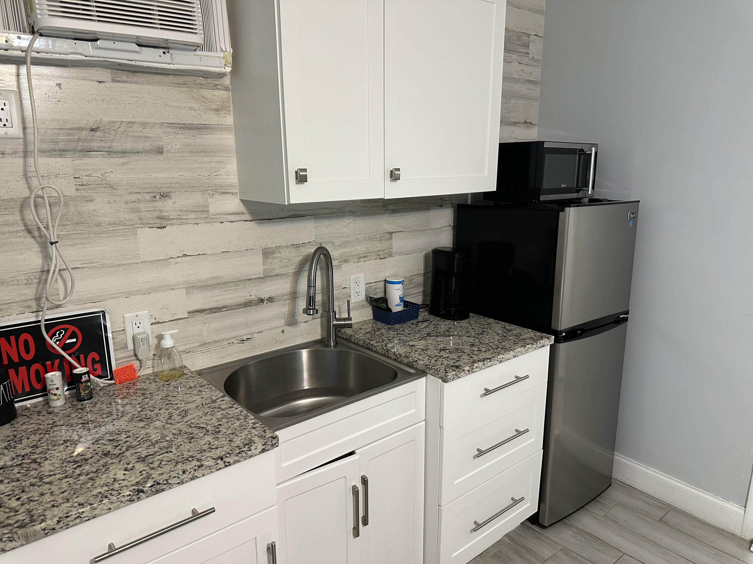 1258 Beach Road, Unit 9 STUDIO Singer Island, FL 33404 - Photo 7 of 13 a kitchen with granite countertop white cabinets sink and stainless steel appliances