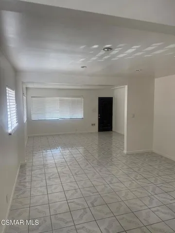 a view of an empty room with window and chandelier