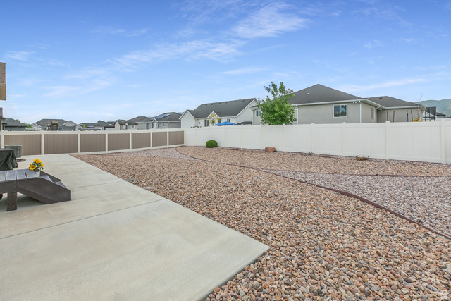 1228 North Providence Way Tooele, UT 84074 - Photo 25 of 28 Expansive backyard featuring a large concrete patio, gravel landscaping, and a combination of beige and white privacy fencing