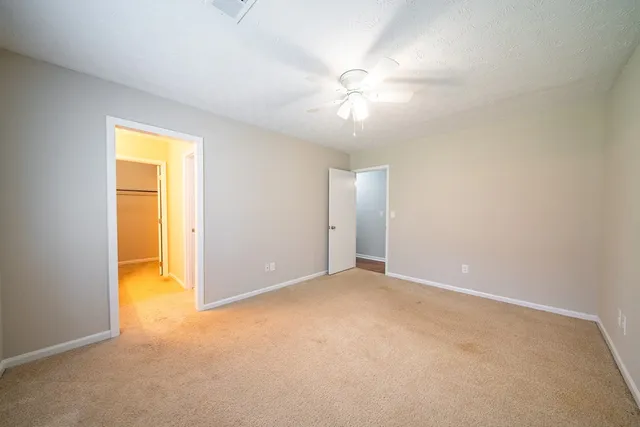 an empty room with a chandelier fan and a window
