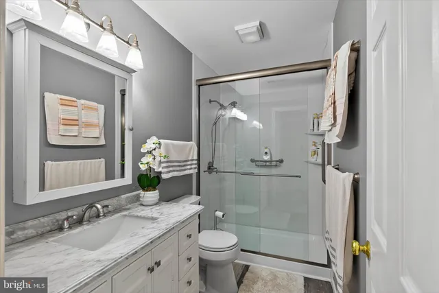 a bathroom with a granite countertop sink toilet a mirror and shower