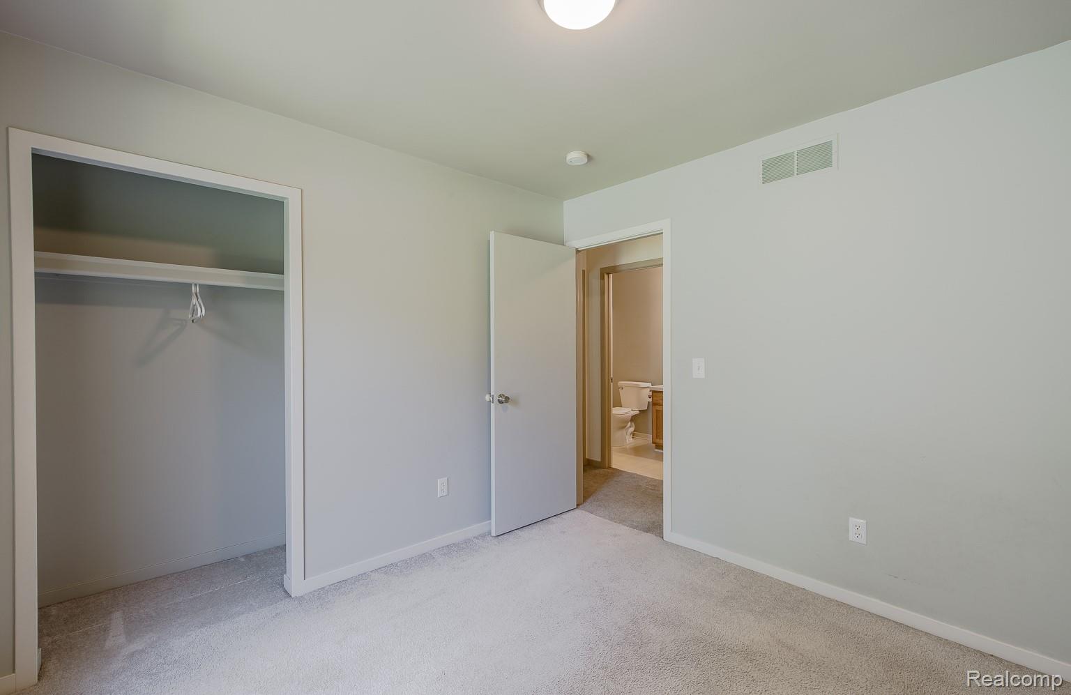 312 Reid Road Highland, MI 48357 - Photo 26 of 47 Carpeted room featuring a built-in closet with shelving and a hanging rod, a flush-mount ceiling light, and light-toned wall finishes