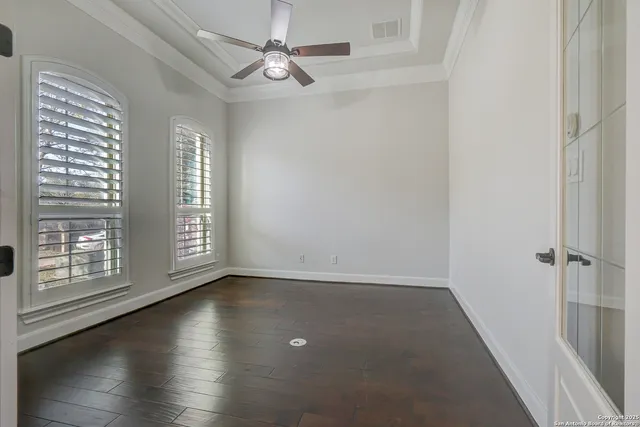 an empty room with wooden floor fan and windows