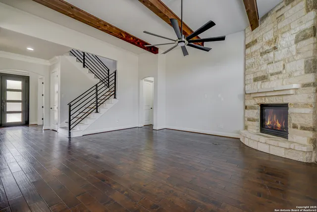 an empty room with wooden floor a ceiling fan and windows