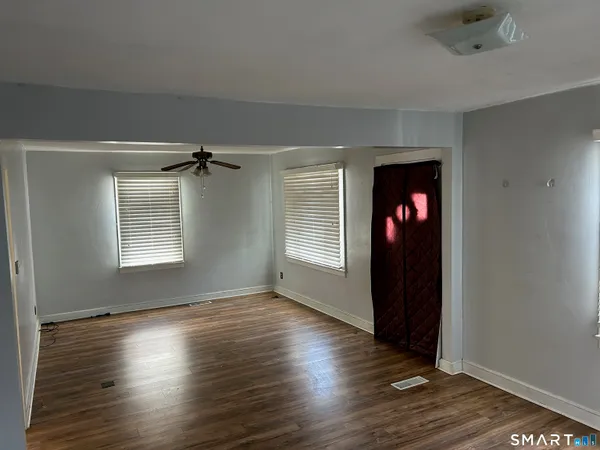 an empty room with wooden floor and windows