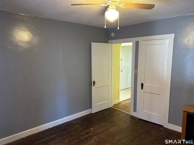 an empty room with wooden floor and hallway