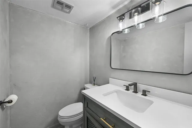 a bathroom with a sink vanity mirror and toilet