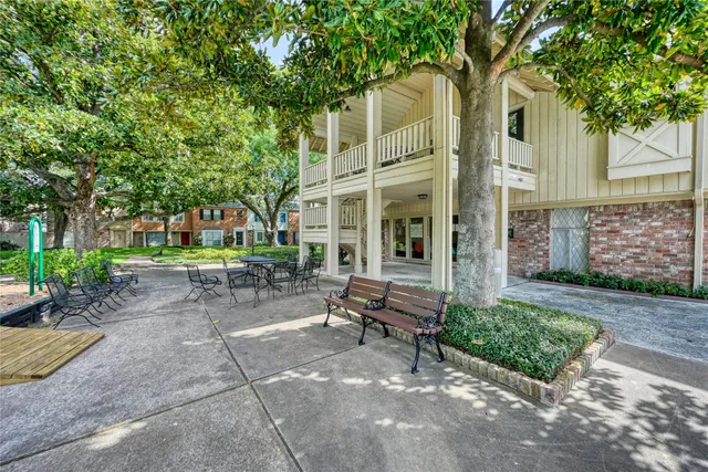 a view of a patio with table and chairs near a large tree