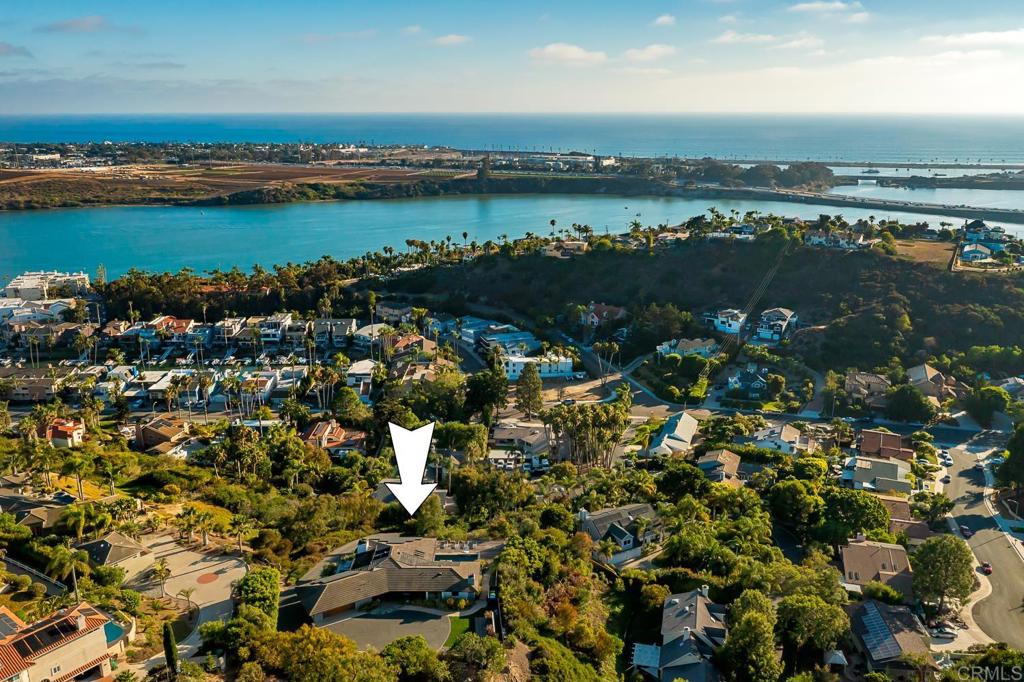 an aerial view of ocean with residential house with outdoor space and trees around