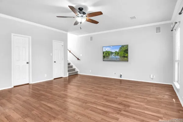 an empty room with wooden floor and windows