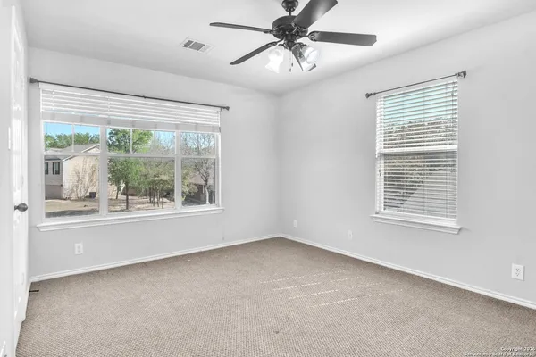 an empty room with wooden floor chandelier fan and windows