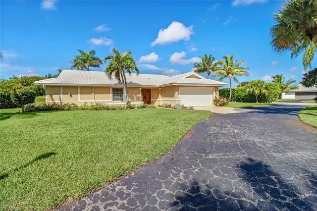 a front view of a house with a yard and potted plants
