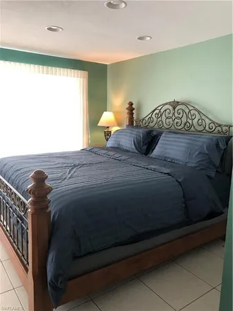 a bed sitting in a bedroom next to a window with lamp on table