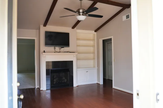 a living room with a fireplace furniture a flat screen tv and a ceiling fan
