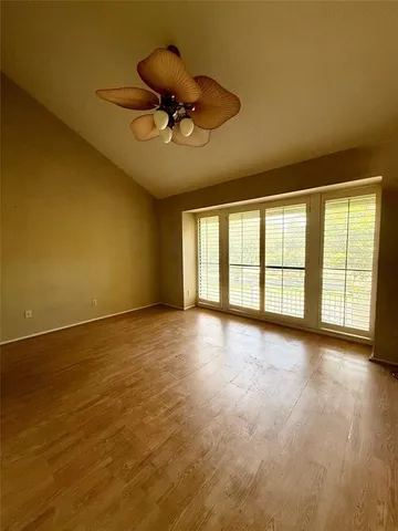 a view of an empty room with a window and wooden floor