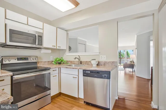a kitchen with granite countertop cabinets stainless steel appliances and wooden floor