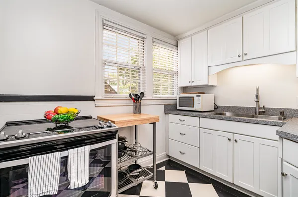 a kitchen with stainless steel appliances a sink a stove and white cabinets