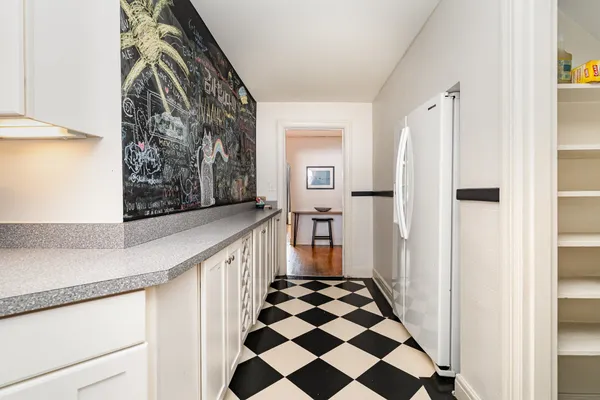 a view of a hallway with white walls and black white checkered floor