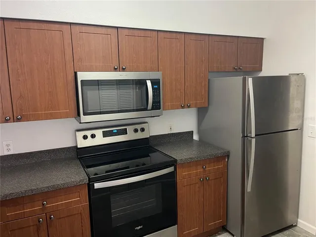 a kitchen with granite countertop a refrigerator stove and microwave