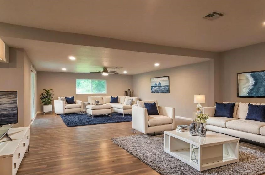 (Virtually Staged) Stylish room with white furnishings, warm wood floors, and a cozy couch.