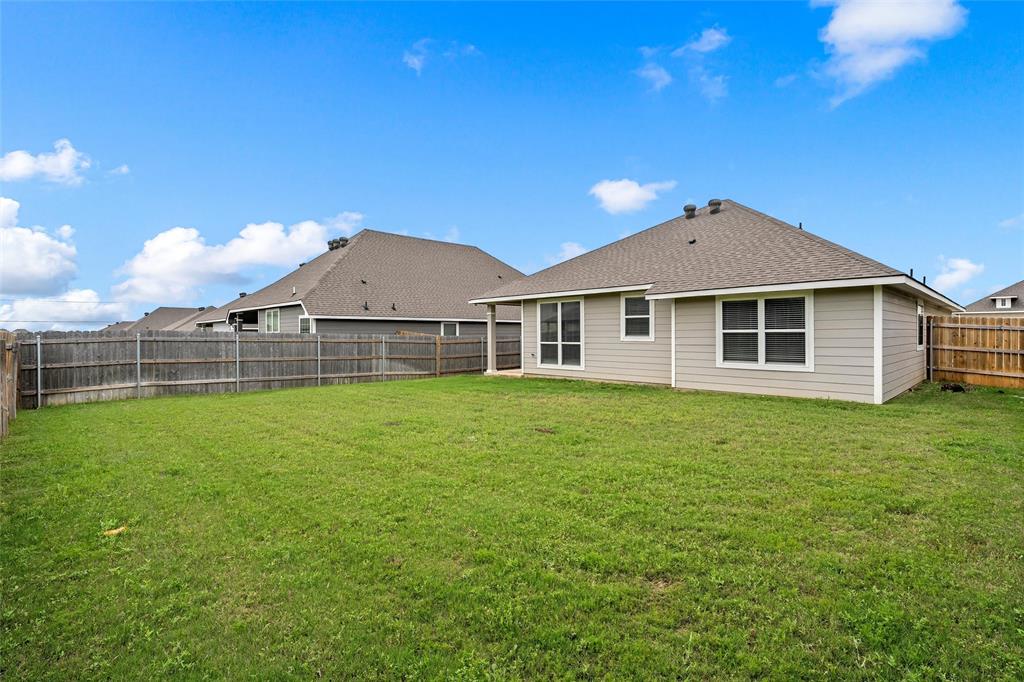 3224 Dottavio Road Lorena, TX 76655 - Photo 29 of 31 Expansive backyard featuring a manicured lawn, full wood fencing, and a light-colored siding exterior with multiple windows