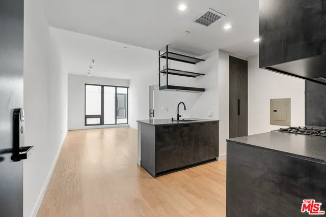 a living room with stainless steel appliances kitchen island a large counter top and a wooden floor