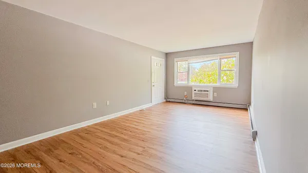 an empty room with a window and wooden floor