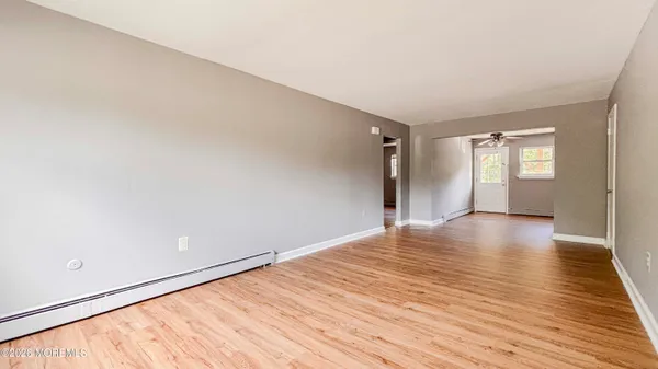 a view of empty room with wooden floor and fan