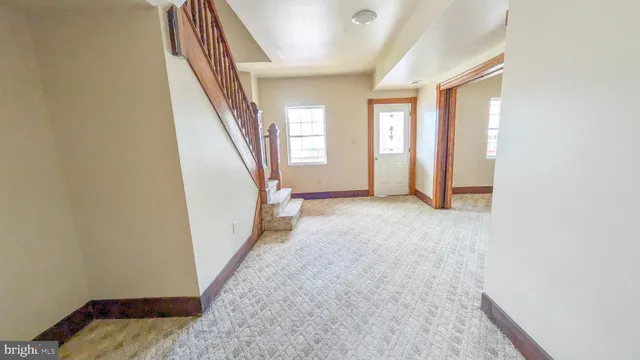 a view of an empty room with wooden floor and stairs
