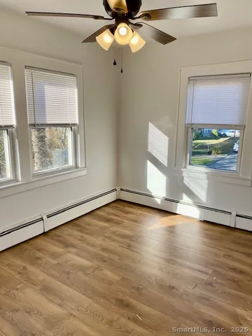an empty room with wooden floor fan and windows