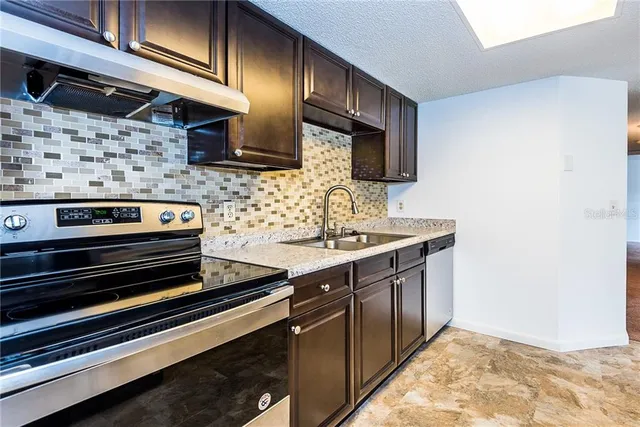 a kitchen with stainless steel appliances granite countertop a sink stove and microwave