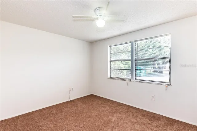 an empty room with a window and a fan