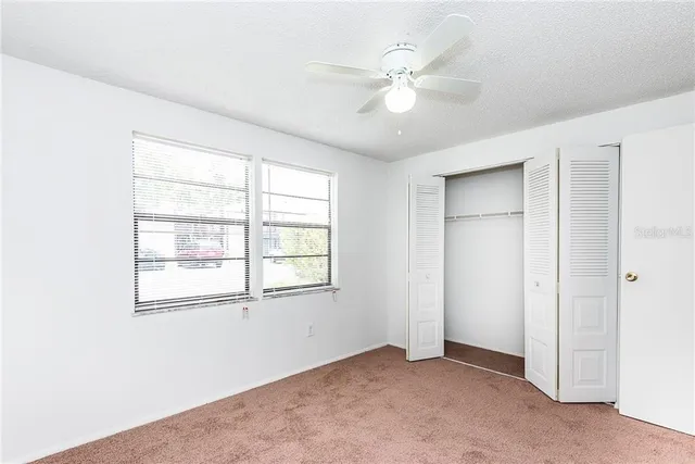 an empty room with windows and fan