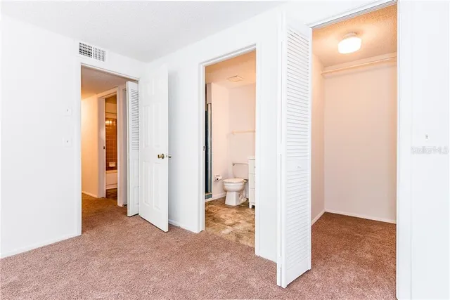 a view of an empty room with bathroom and a window
