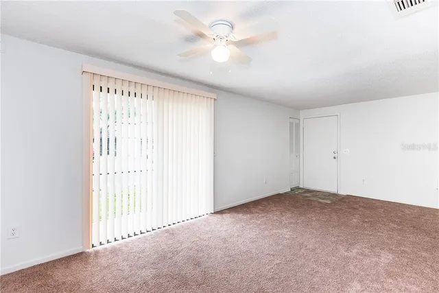 an empty room with windows and fan