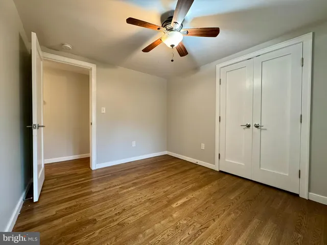 an empty room with wooden floor chandelier fan and closet area