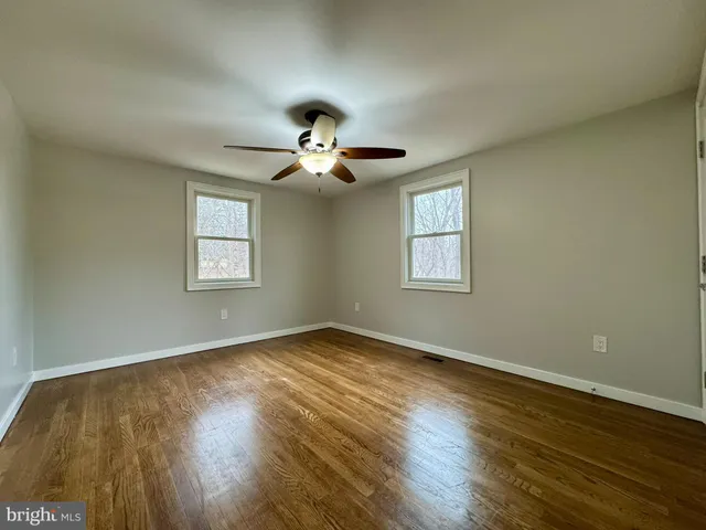 a view of an empty room with a window and wooden floor