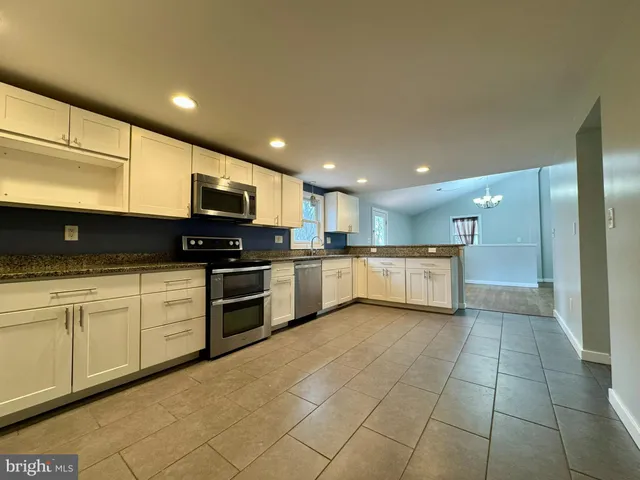 a kitchen with stainless steel appliances granite countertop a sink a stove top oven and cabinets