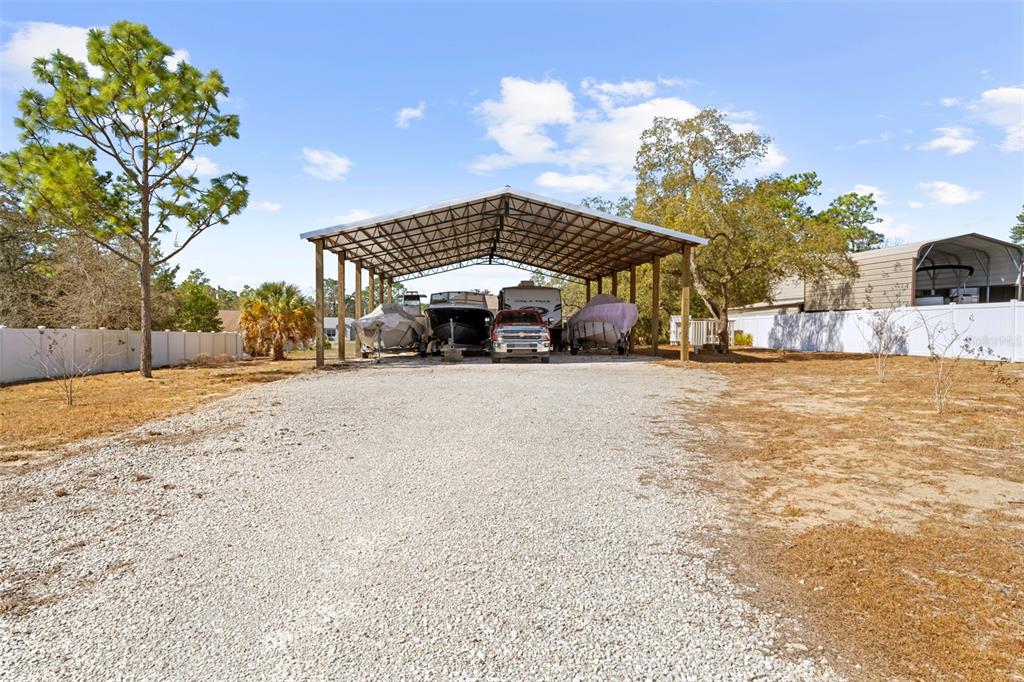 11014 Wren Road Brooksville, FL 34613 - Photo 44 of 50 a blue umbrella sitting in middle of a yard next to a building
