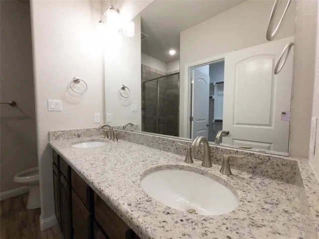 a bathroom with a granite countertop sink a mirror and a toilet