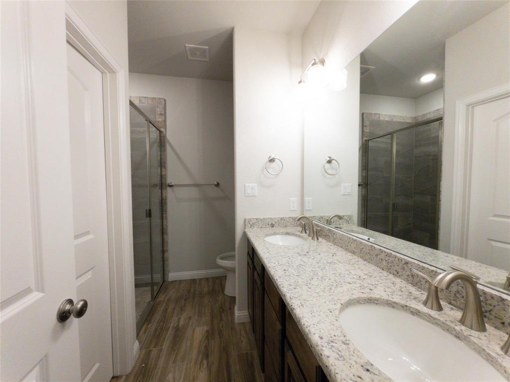245 Honor Code Place Granbury, TX 76049 - Photo 12 of 16 a bathroom with a granite countertop sink a mirror and shower
