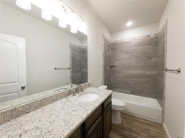 a bathroom with a granite countertop sink a toilet and shower