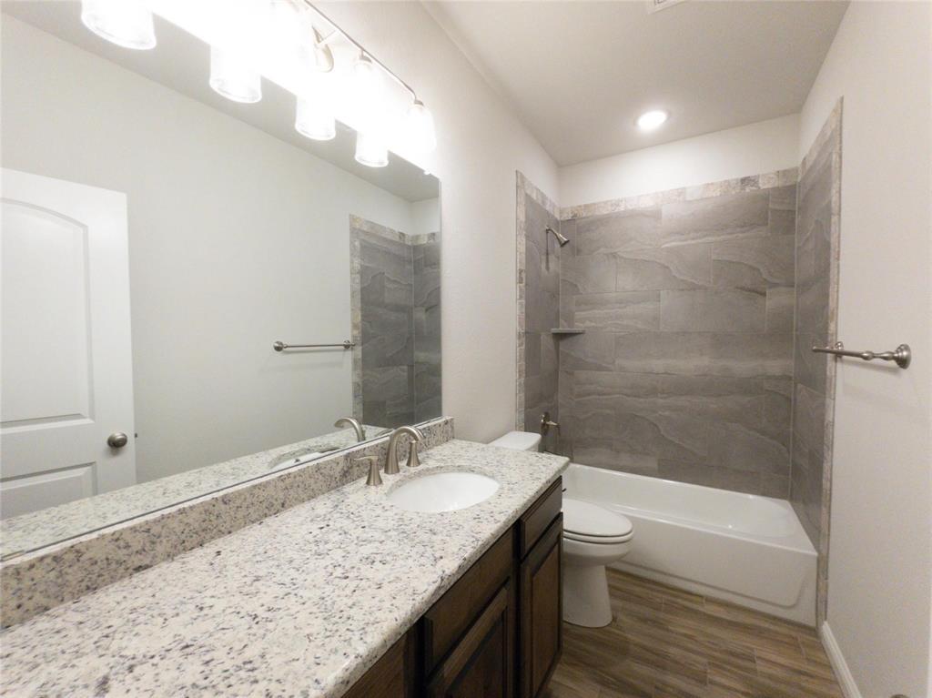 245 Honor Code Place Granbury, TX 76049 - Photo 8 of 16 a bathroom with a granite countertop sink a toilet and shower
