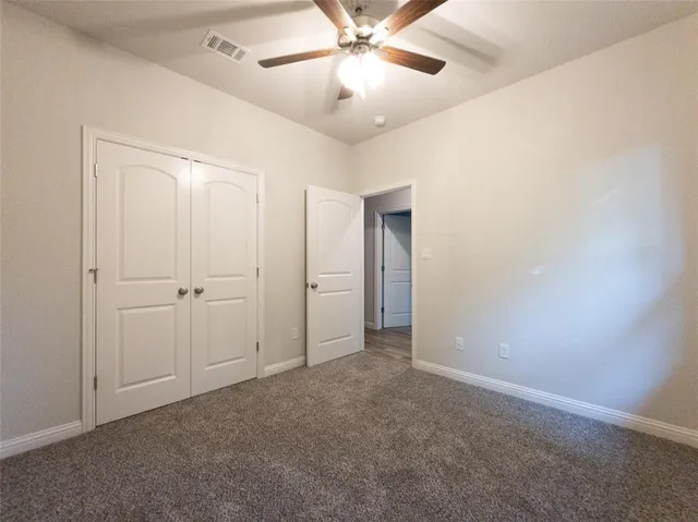 an empty room with closet and a chandelier fan