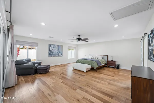 a spacious bedroom with a bed and wooden floor
