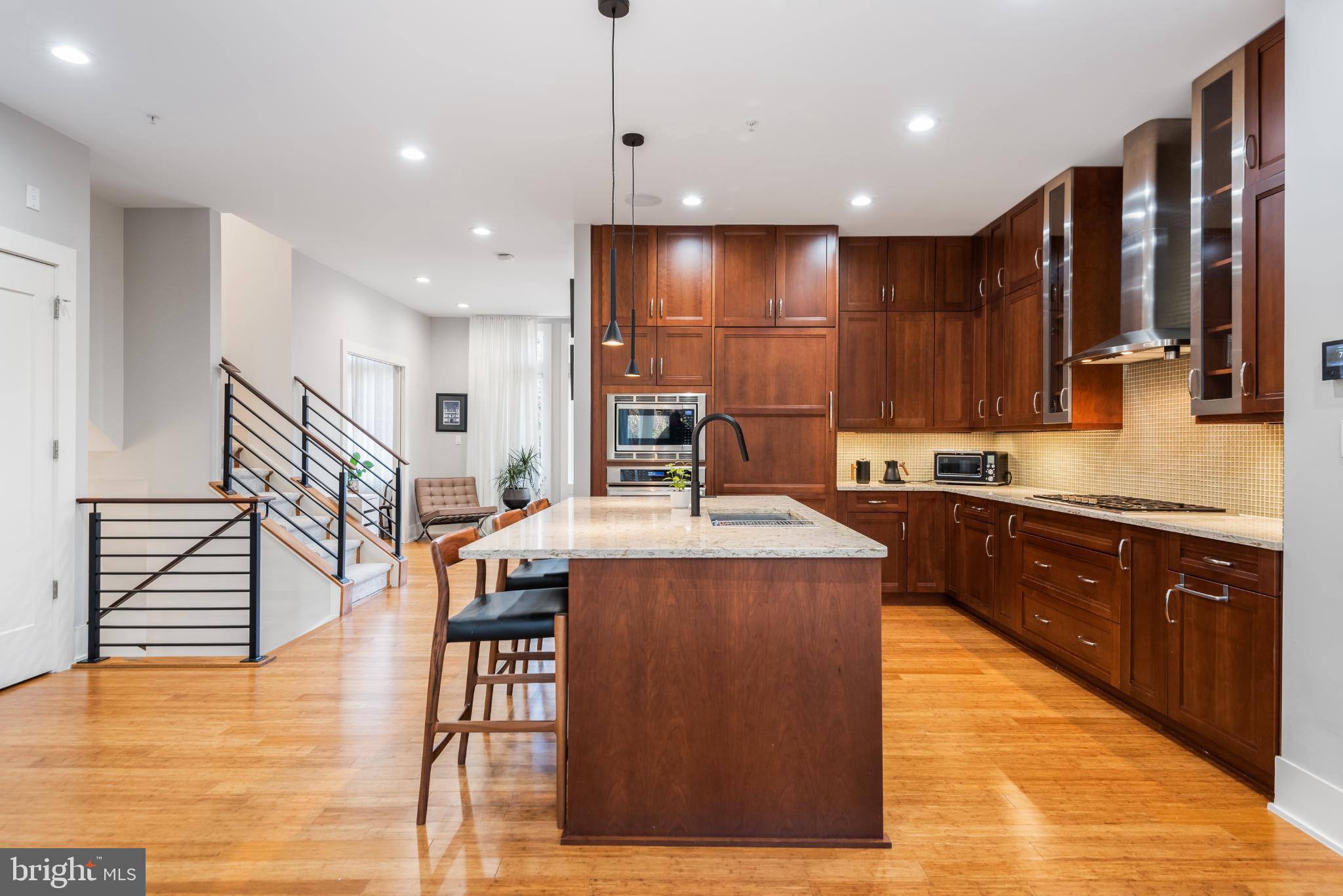 5117 Willet Bridge Road Bethesda, MD 20816 - Photo 14 of 46 a kitchen with stainless steel appliances kitchen island granite countertop wooden floor a stove a sink a dining table and chairs