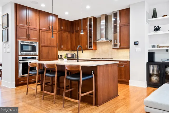a kitchen with stainless steel appliances granite countertop a table chairs sink and cabinets
