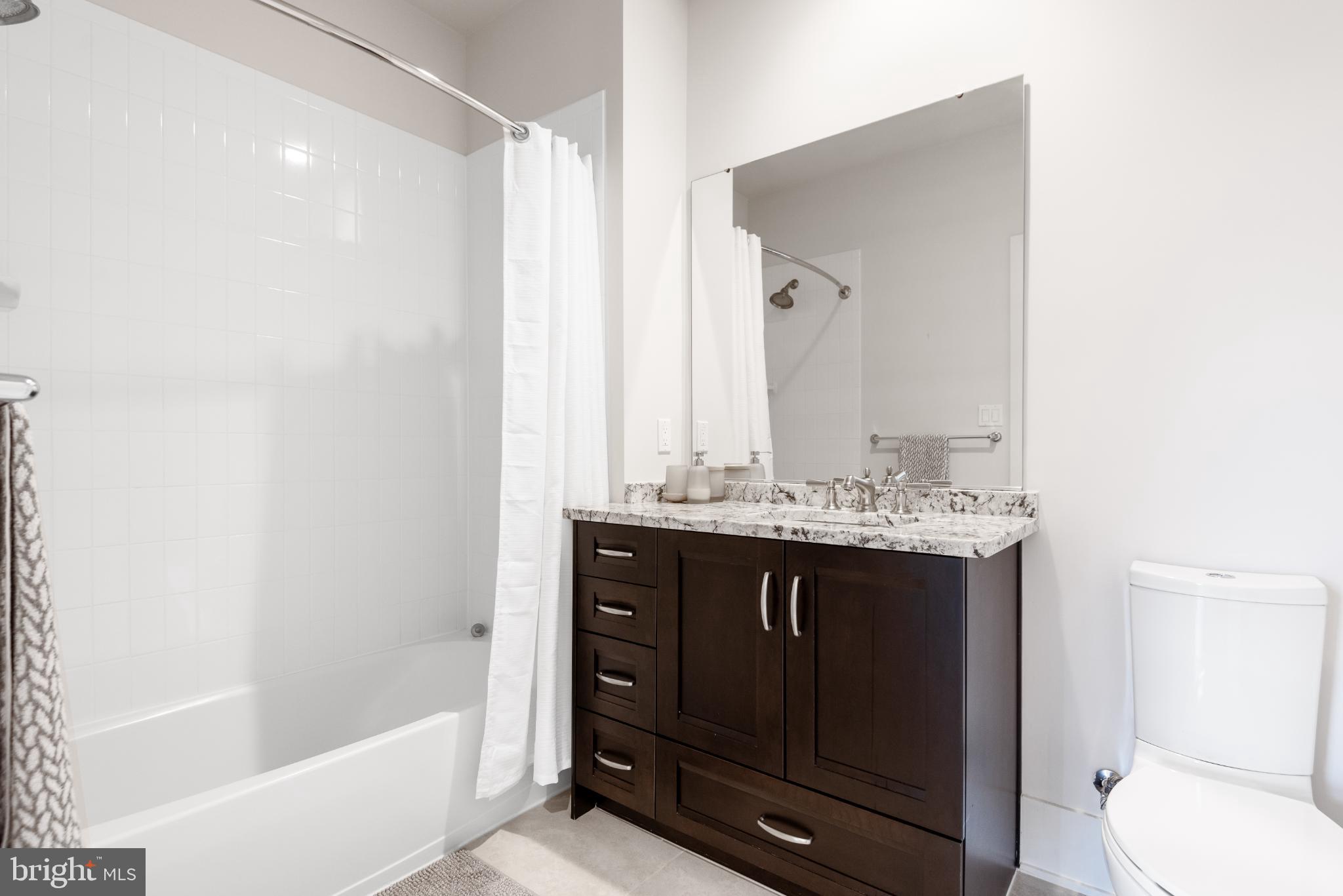 5117 Willet Bridge Road Bethesda, MD 20816 - Photo 34 of 46 a bathroom with a granite countertop sink a toilet and shower