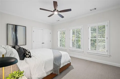 a view of a brick house with a big yard plants and large trees