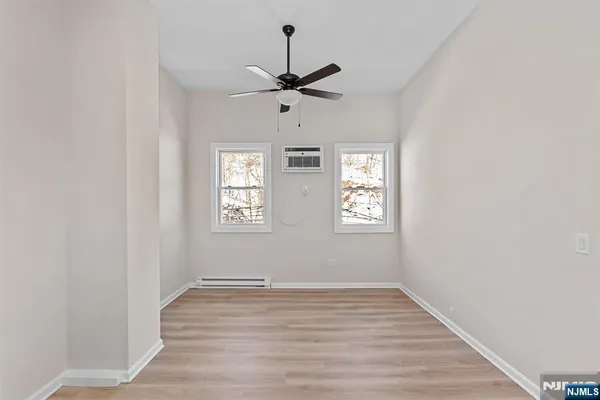 an empty room with wooden floor ceiling fan and windows